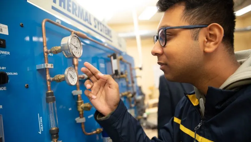 A person looking at a gauge on a piece of equipment that says Thermal Systems at the top