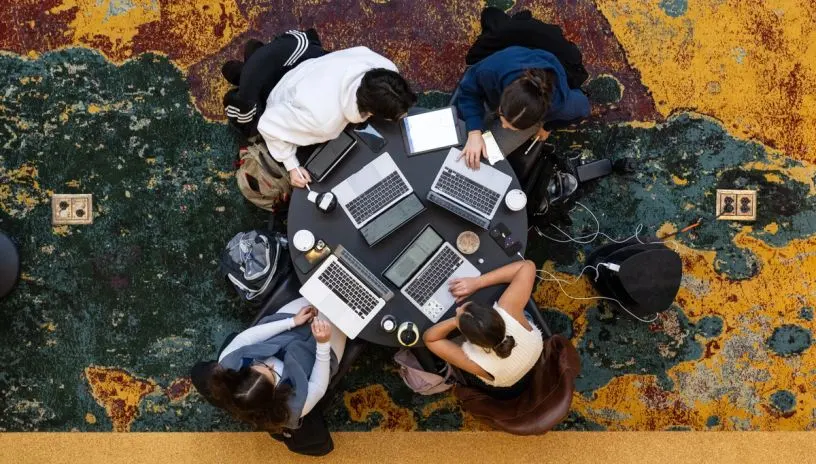 A top-down view of students sitting around a round table