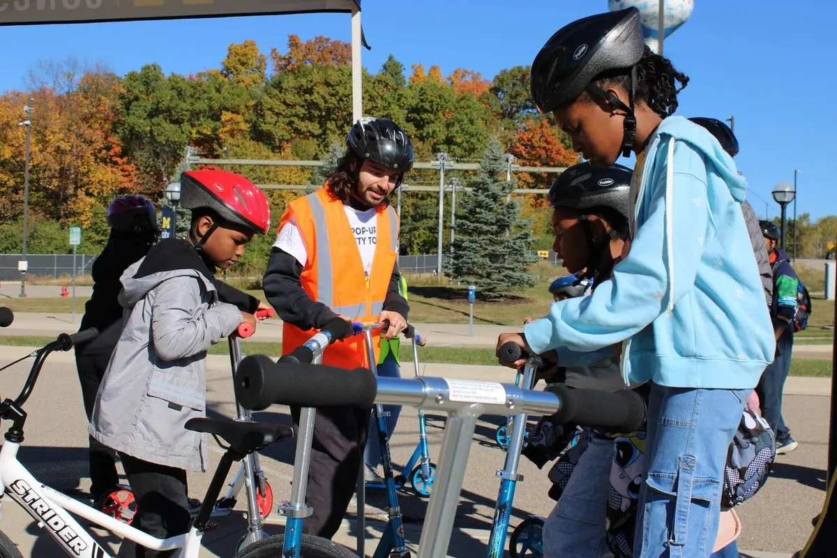 Students preparing to ride scooters during a hands-on traffic safety and STEM event at the University of Michigan's Mcity facility