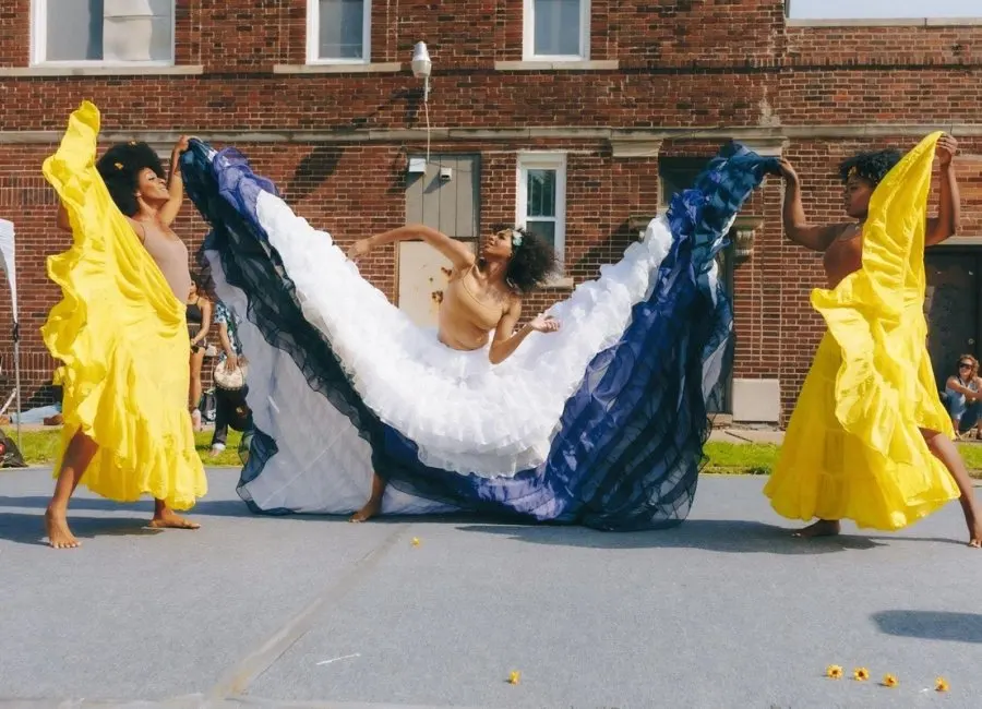 Students dance in colorful dresses on campus