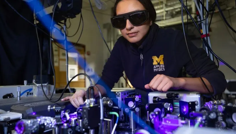 A person wearing dark goggles and adjusting some equipment