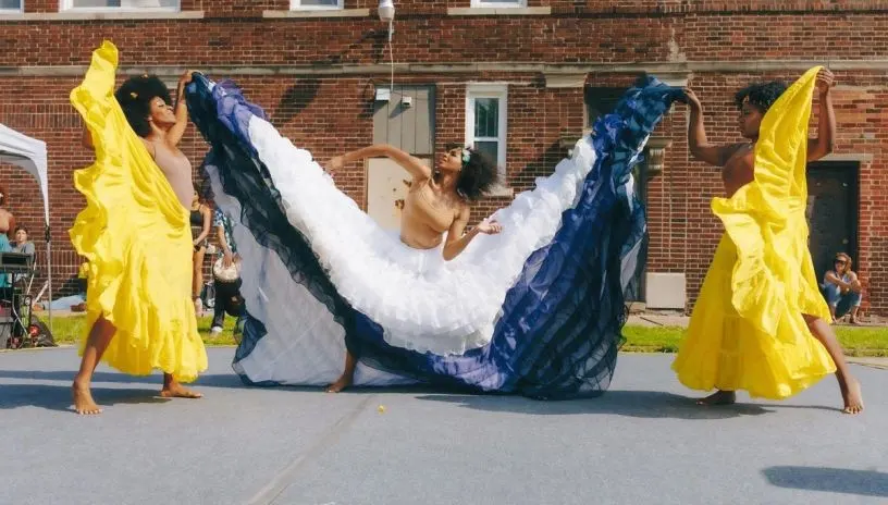 People dancing in colorful dresses on campus