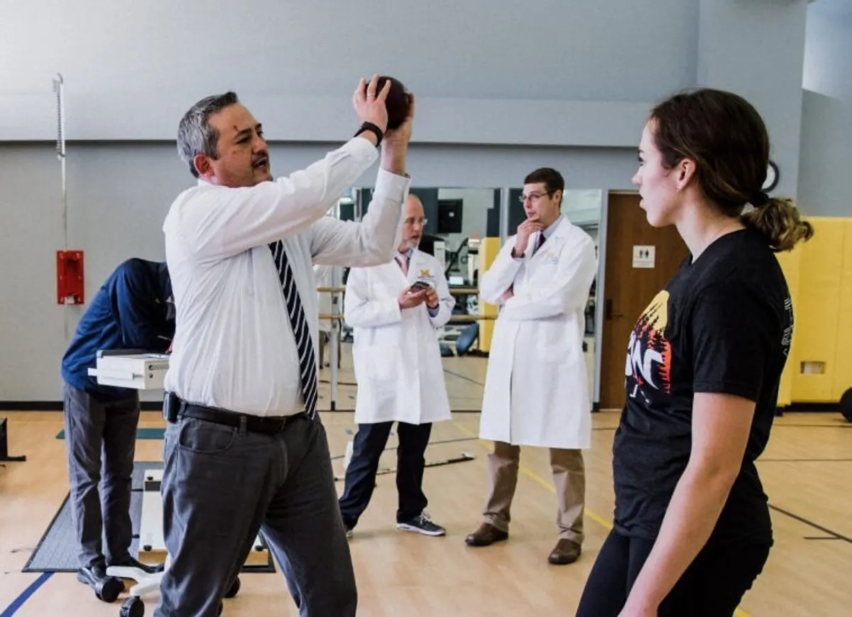 Researchers demonstrating a physical therapy exercise with a small ball